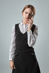 Young girl talking at the cellphone on a gray background