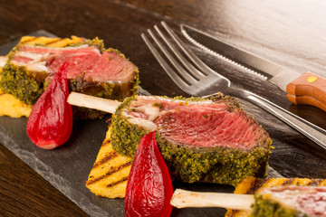 Close up of lamb chops with toasted bread and red onion on a bla