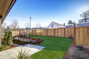 Sloped backyard surrounded by wooden fence Luxury New construction home with open floor plan - 133612126