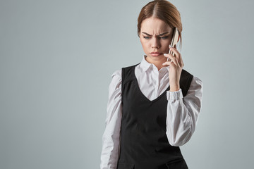 Young girl talking at the cellphone on a gray background