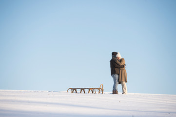 Beautiful senior couple on a walk pulling sledge, winter day.