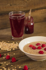 Oatmeal porridge with raspberries and compote on the wooden tabl
