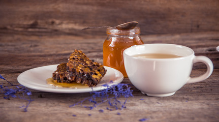Honeycombs and honey in jar and green tea on wooden background