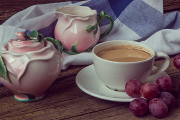 Still life with cup of coffee witj milk, red grapes, pink crocke