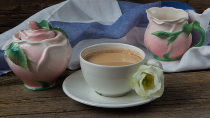 Cup of coffee with milk, red grapes, pink crockery and eustomas