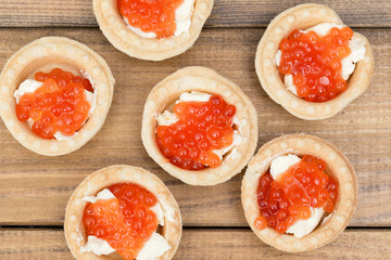 the Several tartlets with red caviar and butter on wooden brown table top view
