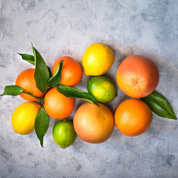 Different citrus fruit on grey concrete table. Orange lime lemon tangerines. Top view © nadianb
