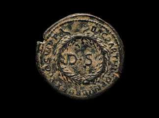 Ancient roman bronze coin with DS letters on it isolated on black