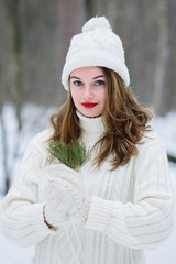 portrait of beautiful woman on the winter background with a sprig of pine