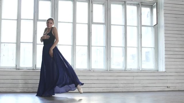 Graceful Ballerina in blue dress dancing and circles in ballet class