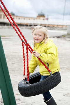 Girl on tire swing, looking at camera