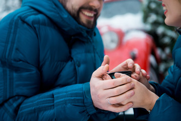 couple warming hands with tea in winter day outdoors