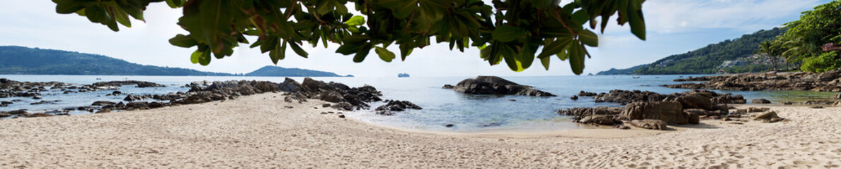 Panorama of tropical island view from the sandy beach with rocks in ocean