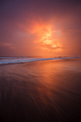 Fototapeta na wymiar Sunset clouds and waves on empty beach