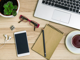 Wooden table with a smartphone, computer and a Cup of tea. The view from the top
