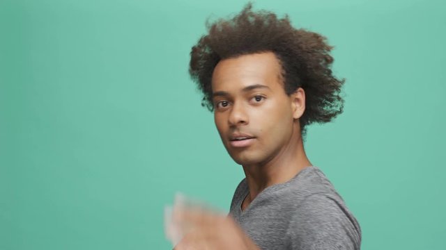 Back view of a happy afro american man turning his head to camera and starting to dance isolated on the green background