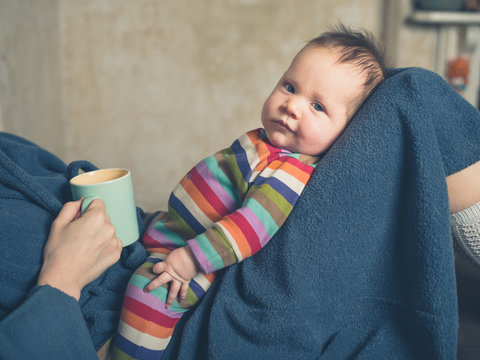 Woman holding baby and drinking tea