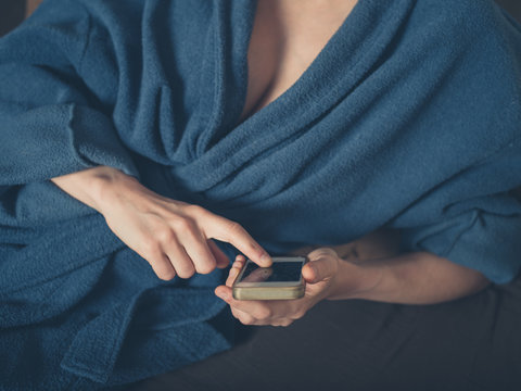 Woman in bathrobe using smartphone
