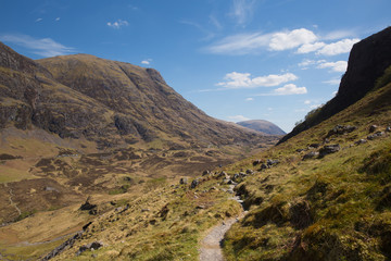 Fototapeta na wymiar Path up to Glencoe snow topped mountains Scotland UK in Scottish Highlands in spring with blue sky and sunshine