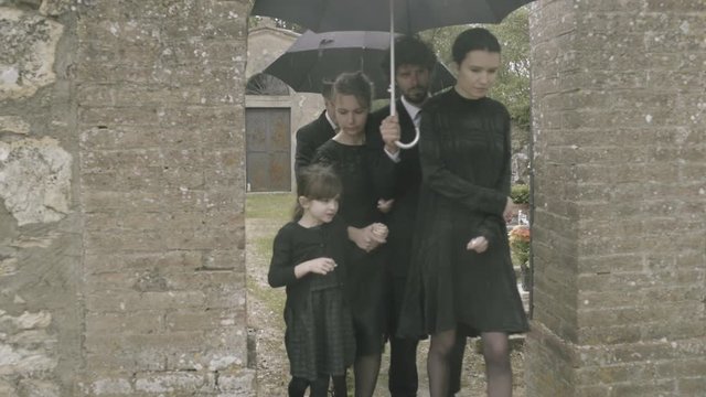Mourners leaving graveyard in the rain