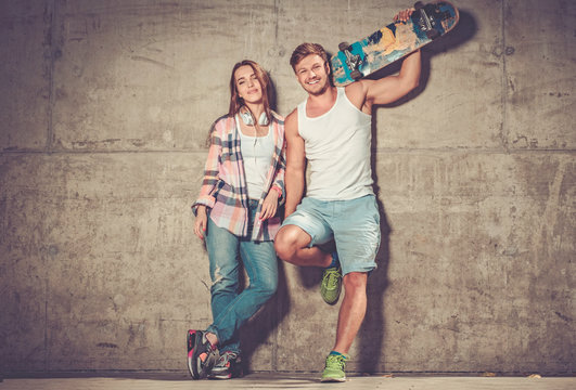Cheerful couple with with skateboard outdoors
