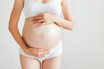 Pregnant woman in white underwear. Young woman expecting a baby.