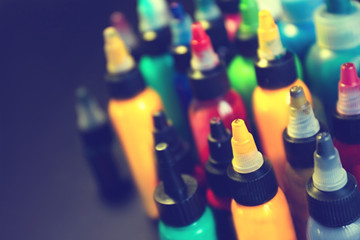 Multiple bottles with colorful inks for tattoo, close up view