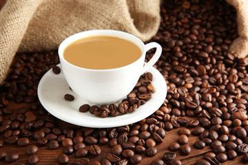 Cup of coffee with beans on table