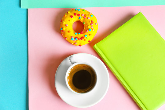 Delicious donut and cup of coffee on color background