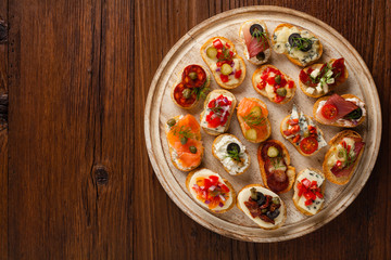 Crostini with different toppings on wooden background. Delicious appetizers. Top view.