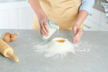 Female hands preparing dough on kitchen table