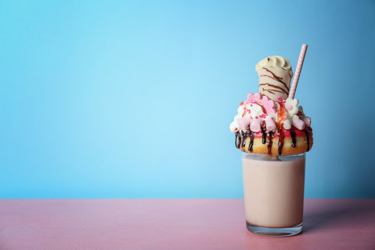 Milkshake, donut and other sweets in glass on blue background