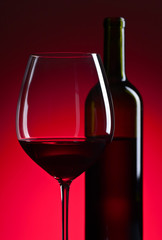 glass and bottle with red  wine on red background