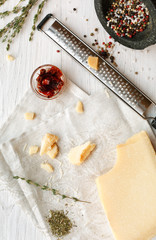 Parmesan piece with small grater and herbs top view