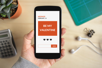 Hand holding smart phone with valentine's day concept on screen. All screen content is designed by me. Flat lay
