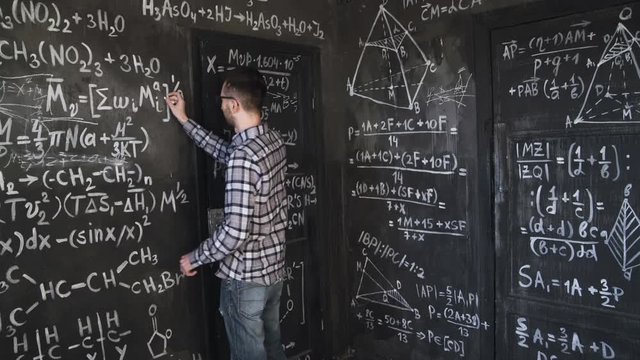 Young scientist man write chock in chemical and mathematical equations wall room interior timelapse