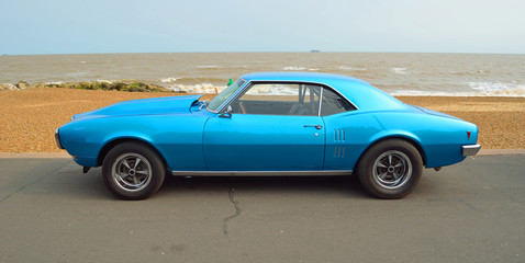 Fototapeta na wymiar Classic Blue motor car parked on seafront promenade.