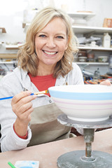 Mature Woman Decorating Bowl In Pottery Class