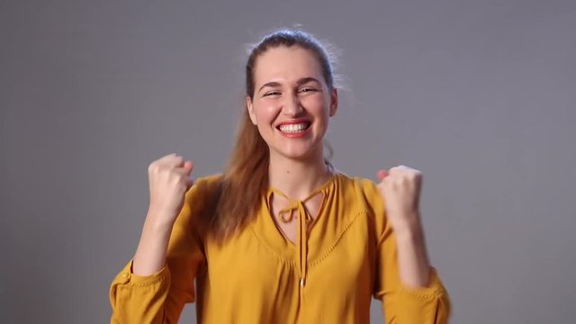 giggling young woman laughing and dancing with successful hand gesture