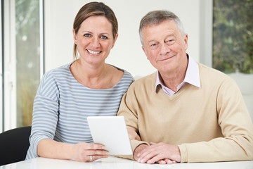 Senior Man And Adult Daughter Looking At Digital Tablet Together