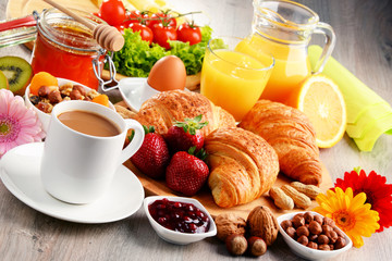 Breakfast consisting of croissants, coffee, fruits, orange juice