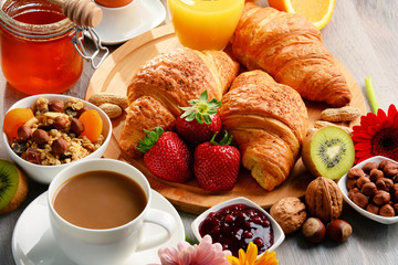 Breakfast consisting of croissants, coffee, fruits, orange juice