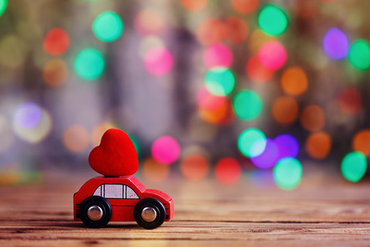 Miniature Car carrying a Red Heart on roof. Holiday concept love