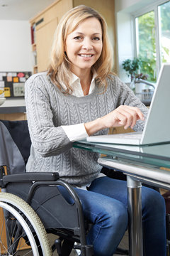 Disabled Woman In Wheelchair Using Laptop At Home