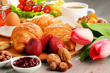 Breakfast consisting of croissants, coffee, fruits, orange juice