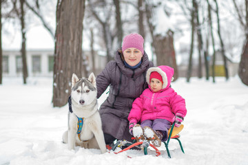 Fototapeta na wymiar little girl her mom with husky dog winter park