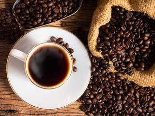 Hot coffee with cup and coffee bean bag on old wood background
