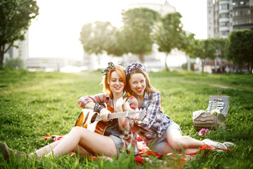 Two young hipster girls having fun on the picnic