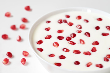 Pomegranate seeds in yogurt in a white Cup