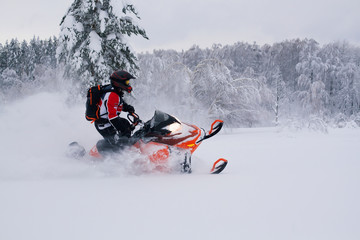Athlete on a snowmobile moving in the winter forest
